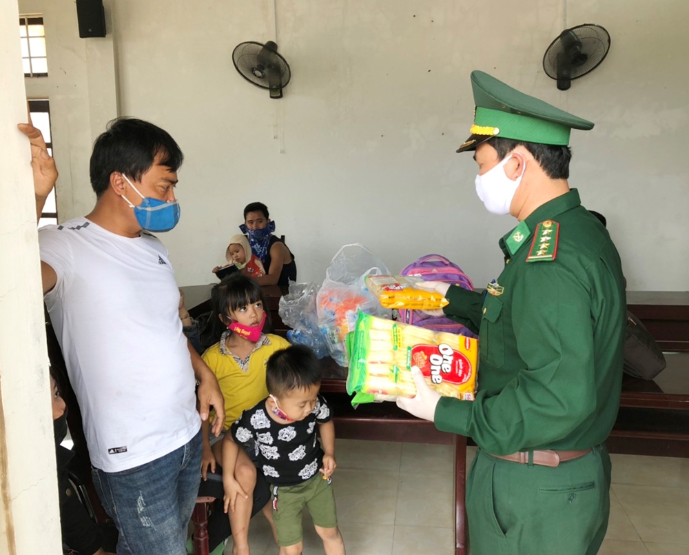 Đồn Biên phòng CKQT La Lay, BĐBP Quảng Trị phát bánh kẹo cho trẻ em trong khi chờ đến khu cách ly 14 ngày theo quy định. Ảnh: Hoàng Quân.